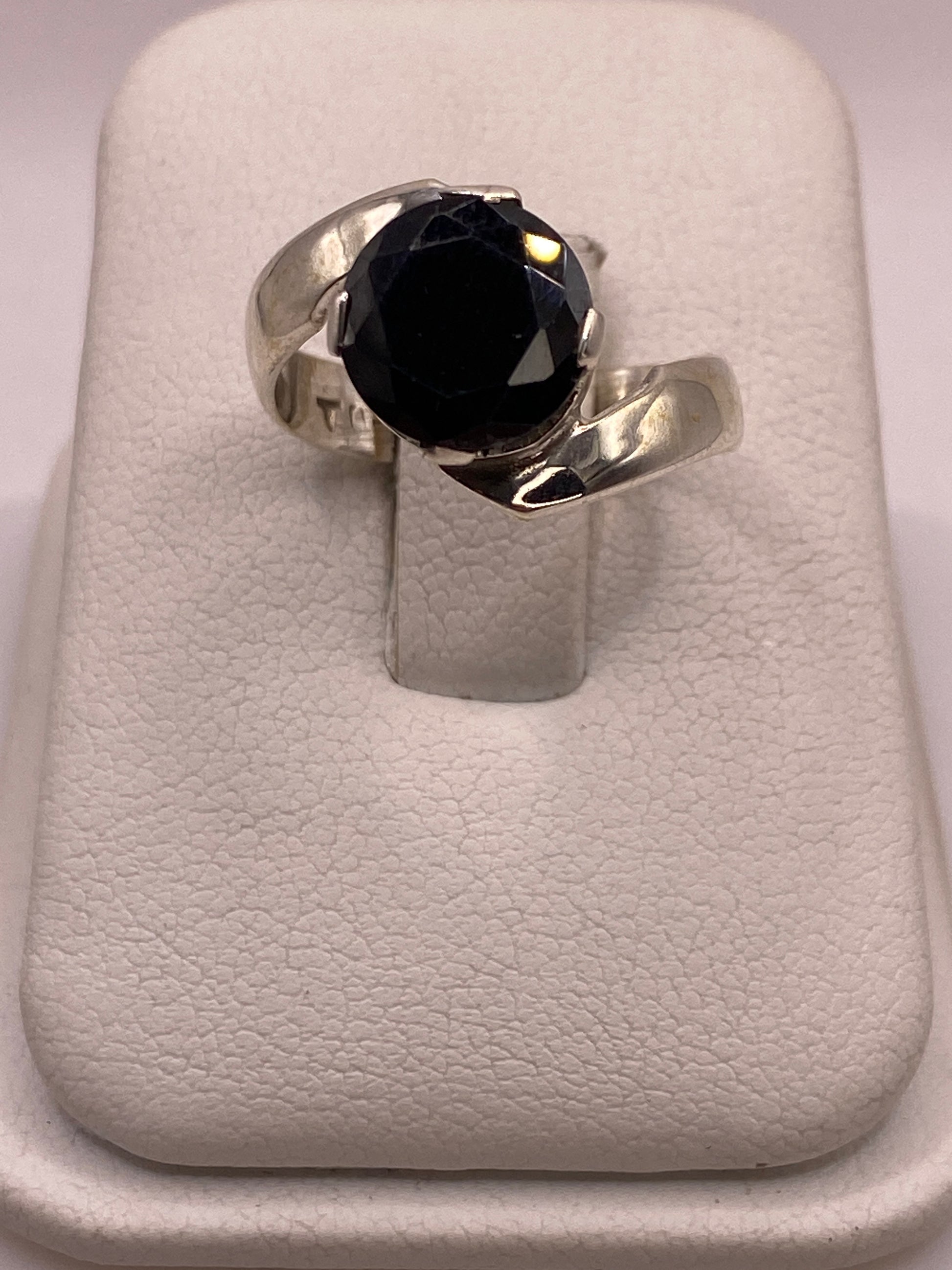 Anillo de plata solitario con circonia negra grande en la mano de una mujer, frente brillante