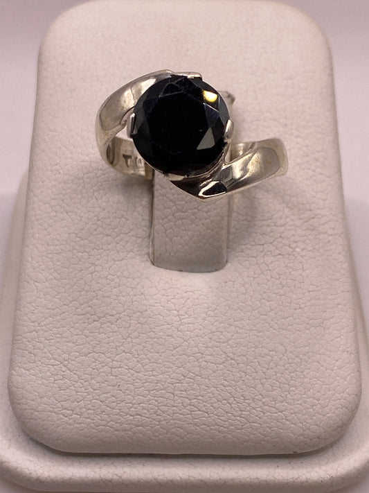 Anillo de plata solitario con circonia negra grande en la mano de una mujer, frente brillante