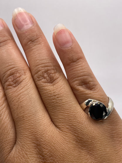 Anillo de plata solitario sobre fondo azul mostrando el brillo negro de la circonia facetada