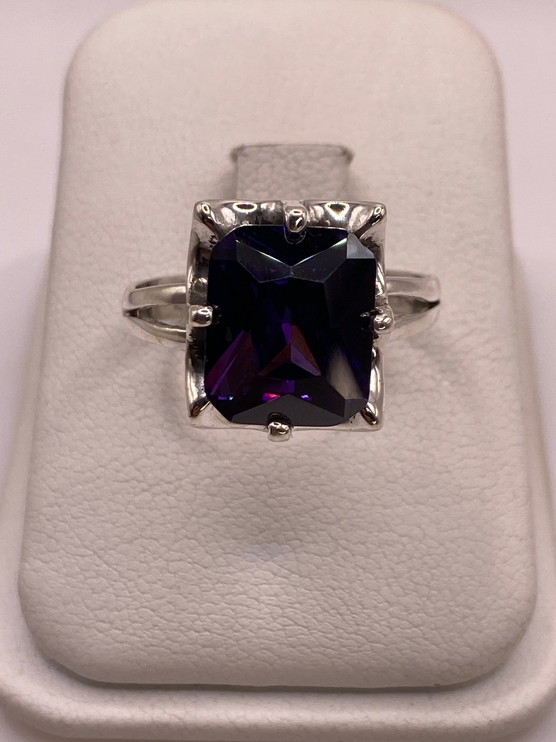 Anillo solitario de plata con circonia púrpura profundo en mano de mujer