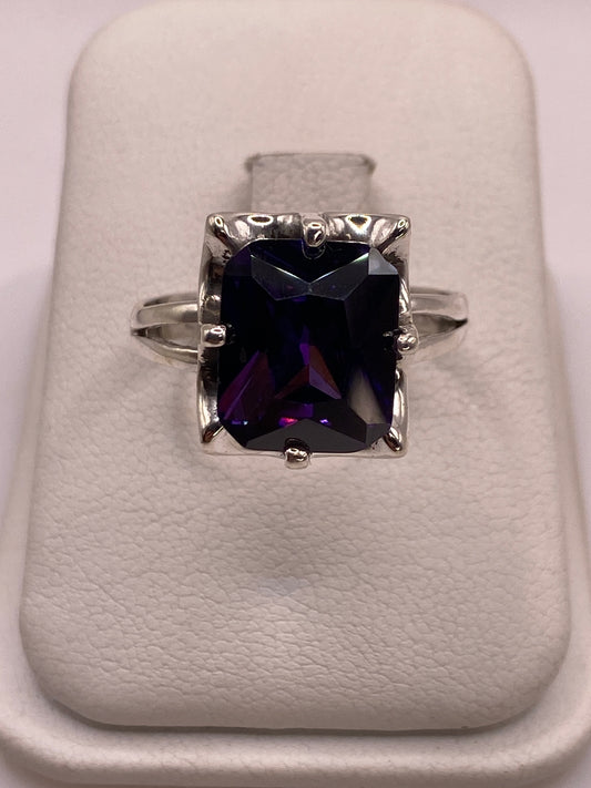 Anillo solitario de plata con circonia púrpura profundo en mano de mujer