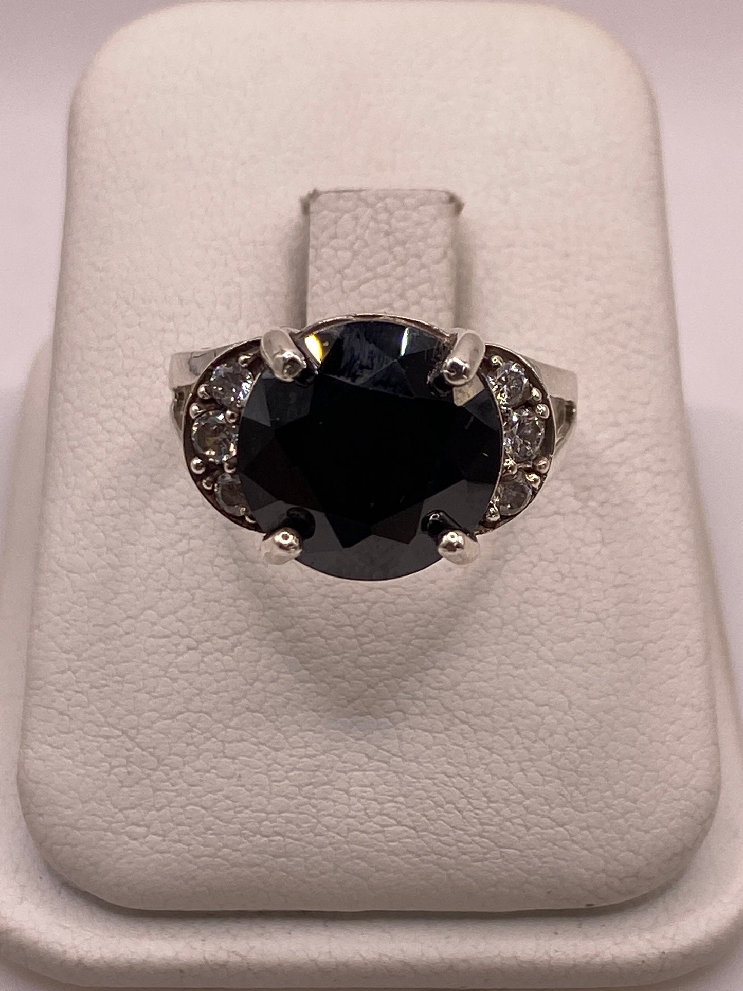 Anillo solitario de plata con circonia ovalada incolora, vista frontal sobre almohada blanca