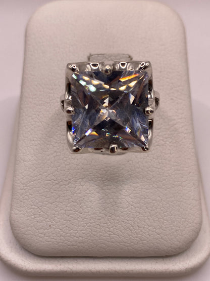 Anillo solitario de plata .925 con circonia blanca cuadrada, frente 10 mm, sobre almohada blanca