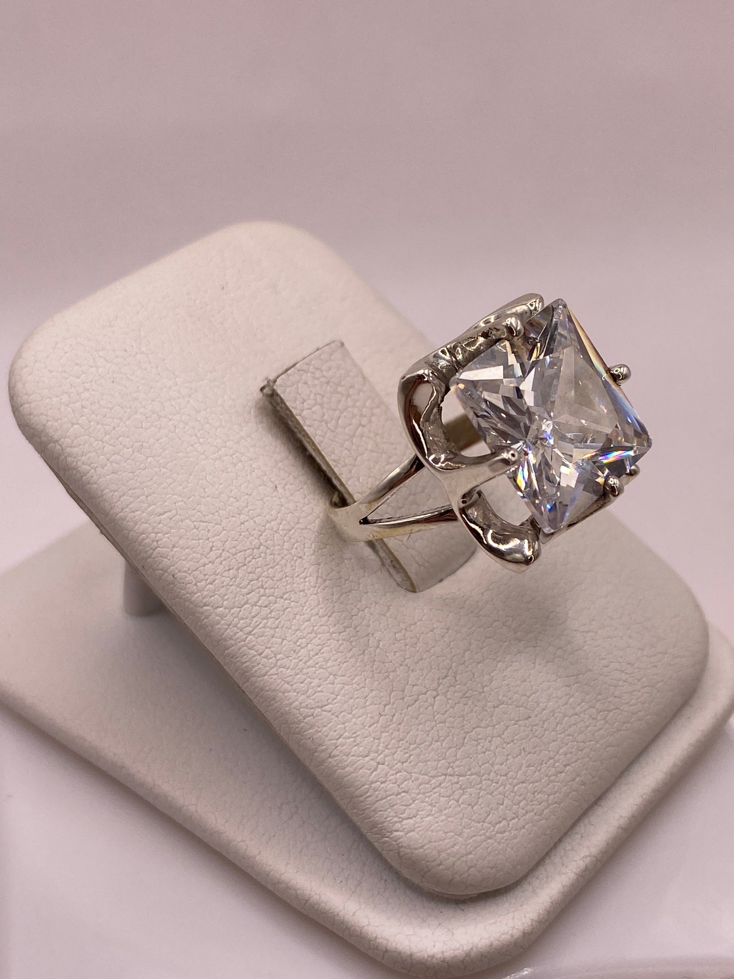 Anillo coctel de plata con circonia blanca reflejando luz como diamante, vista frontal