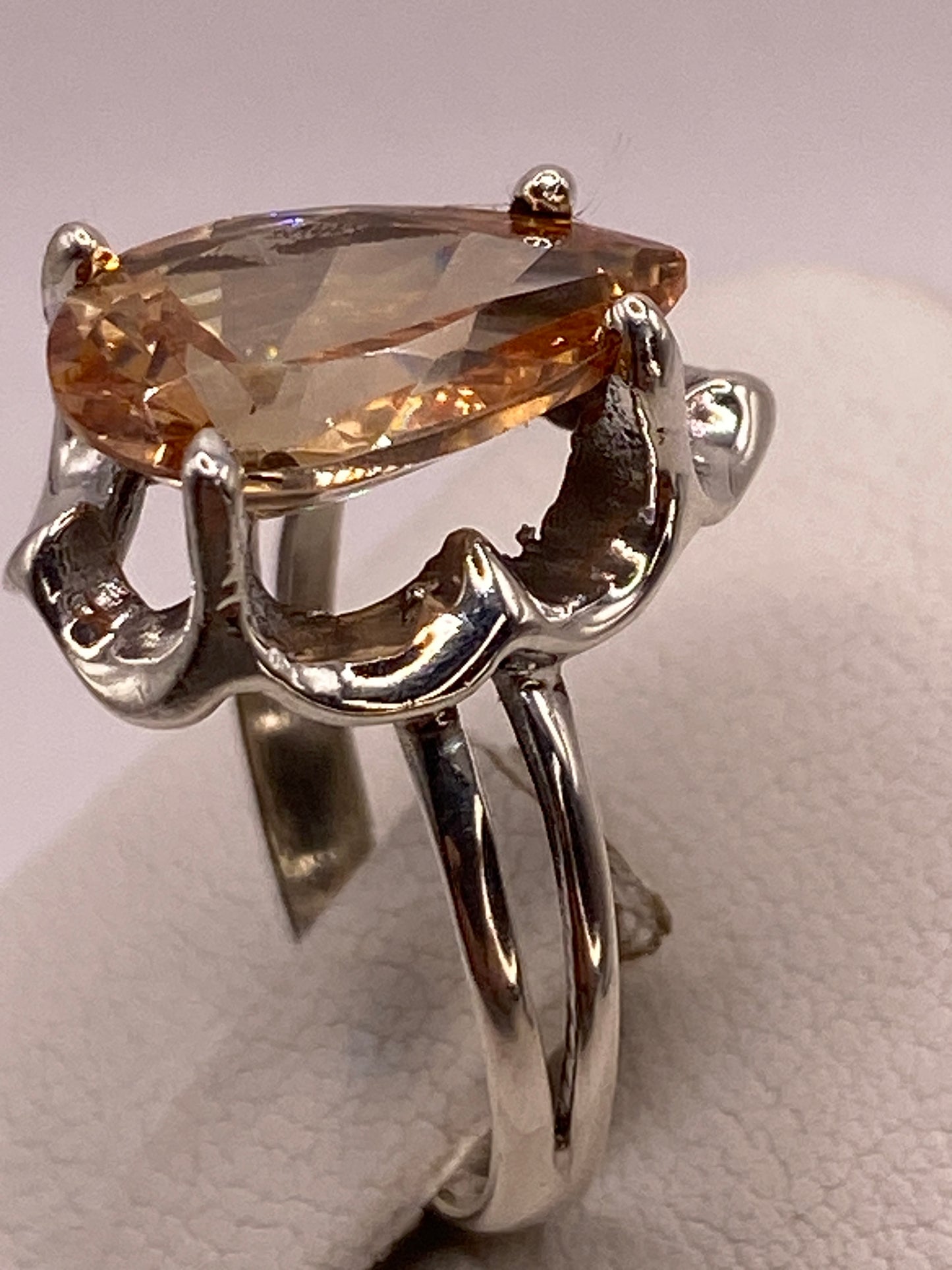 Anillo solitario de plata en la mano mostrando el brillo ámbar dorado de la piedra