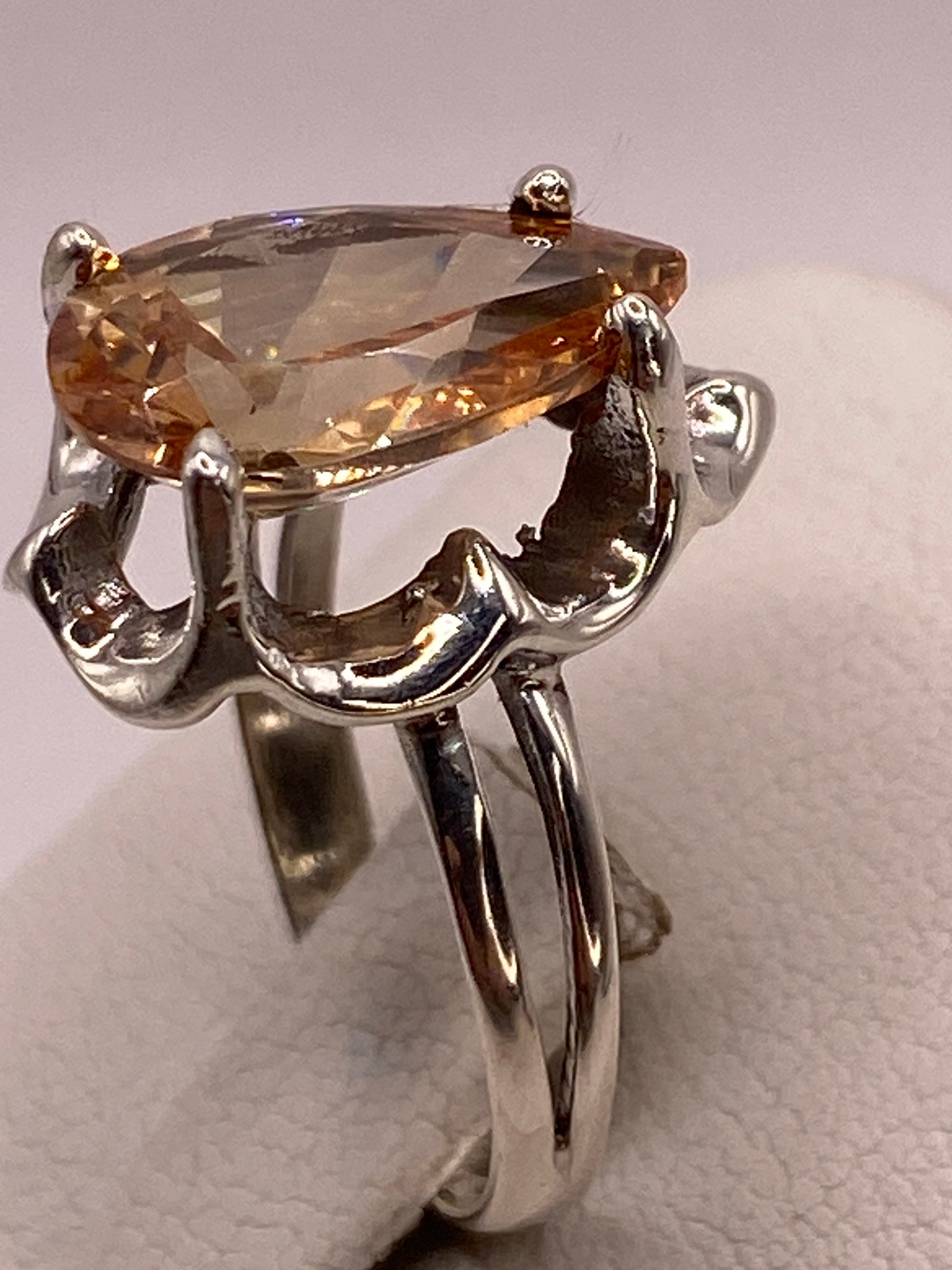 Anillo solitario de plata en la mano mostrando el brillo ámbar dorado de la piedra