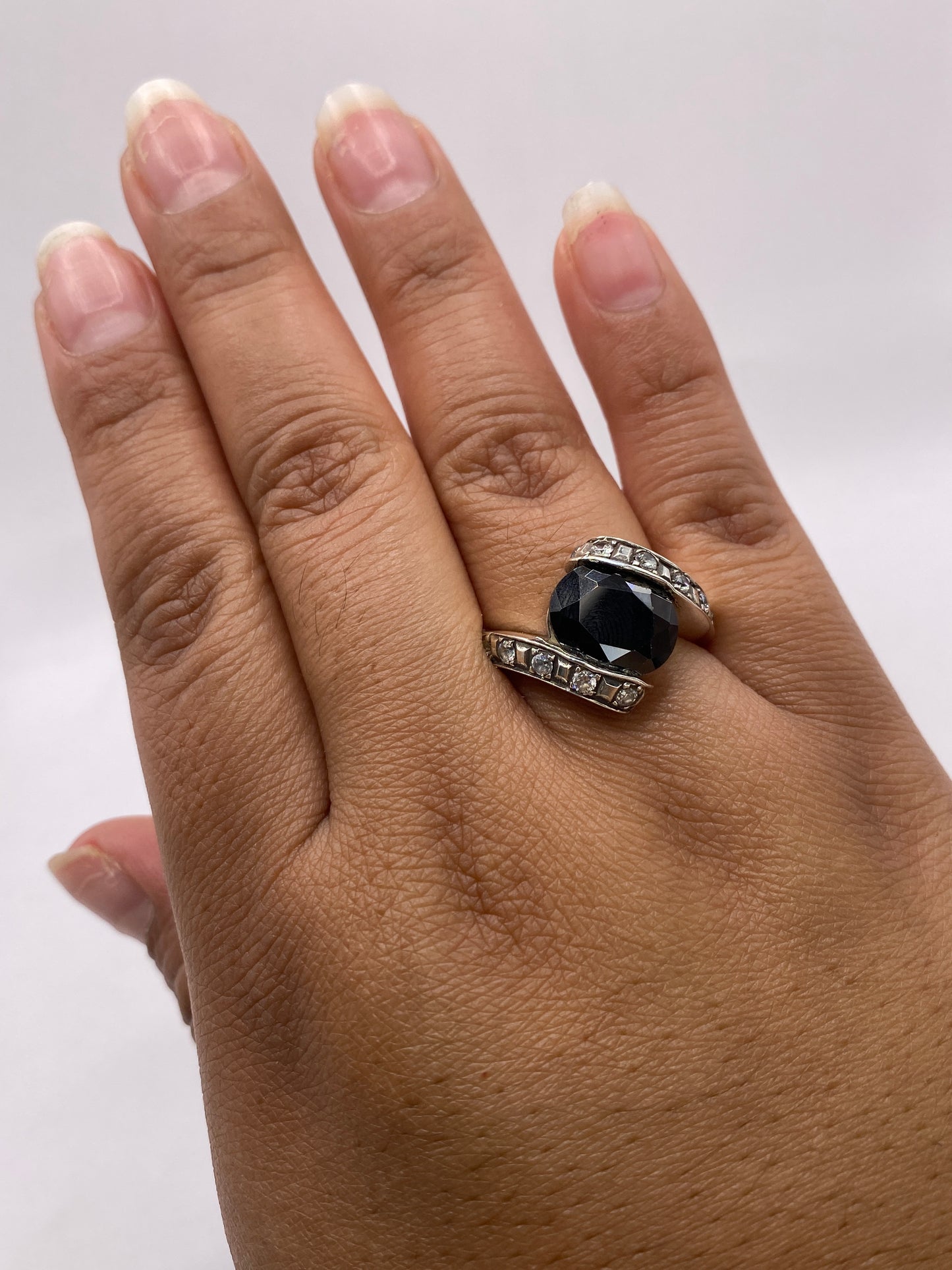 Anillo puesto en dedo de mujer adulta, mostrando contraste del ónix negro y brillo de circonia blanca