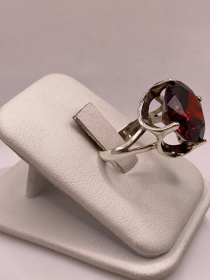 Vista lateral del anillo de plata con engaste de circonia roja en estilo coctel