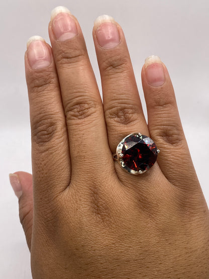 Anillo solitario en mano mostrando el brillo de la circonia roja bajo luz natural