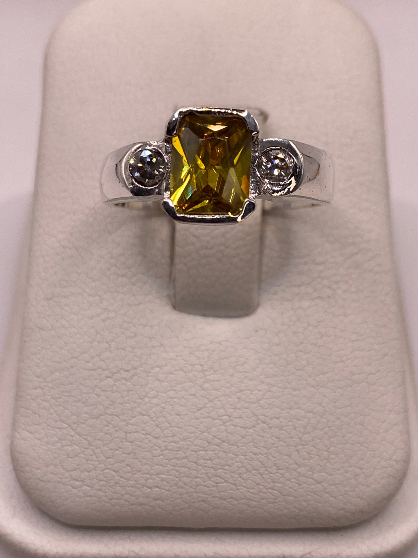 Anillo solitario de plata .925 con circonia amarilla en talla rectangular, visto de frente en estuche blanco