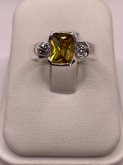 Anillo solitario de plata .925 con circonia amarilla en talla rectangular, visto de frente en estuche blanco