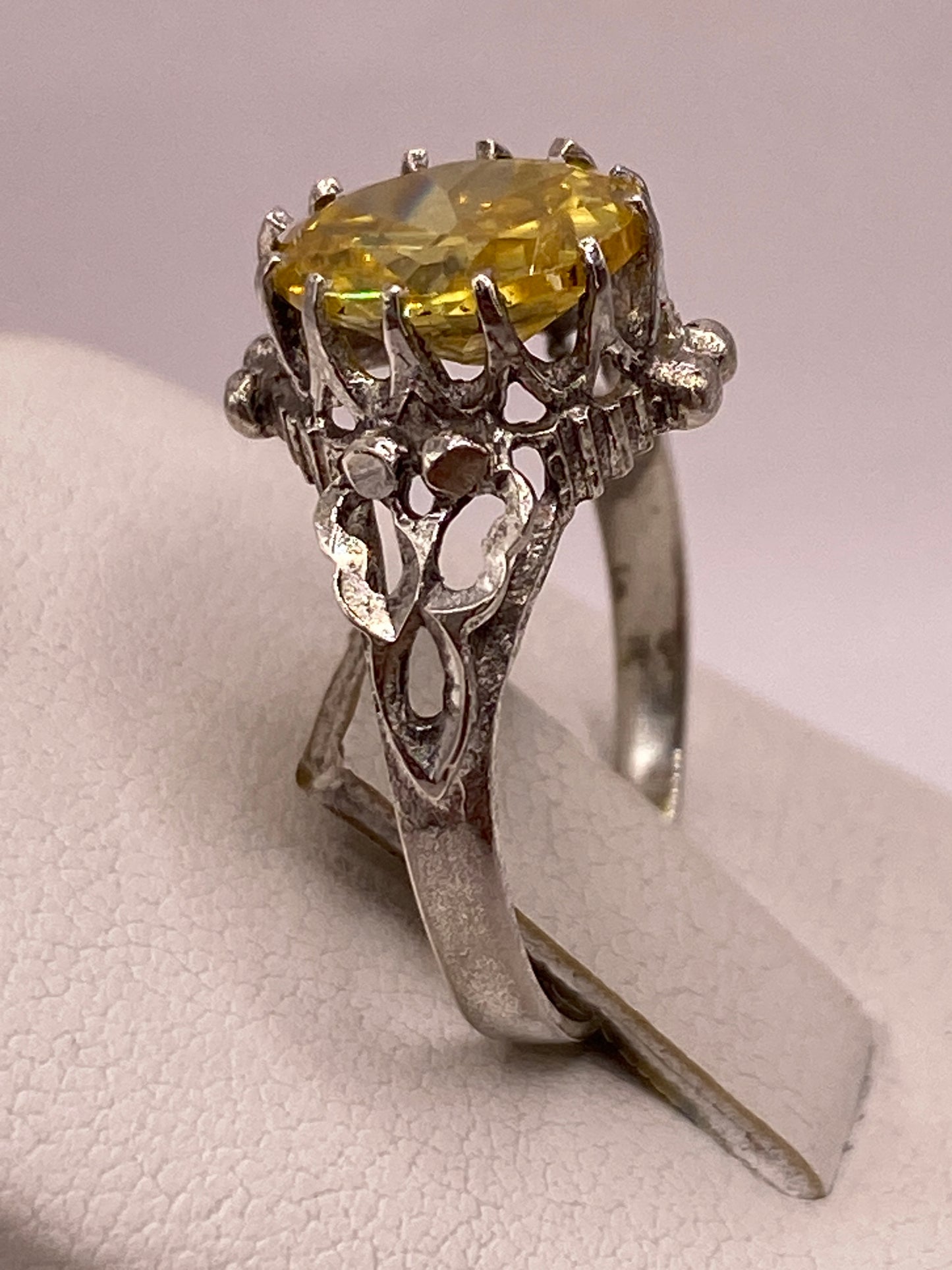 Vista superior del anillo con circonia amarilla facetada brillando contra fondo blanco