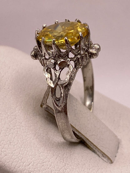 Vista superior del anillo con circonia amarilla facetada brillando contra fondo blanco