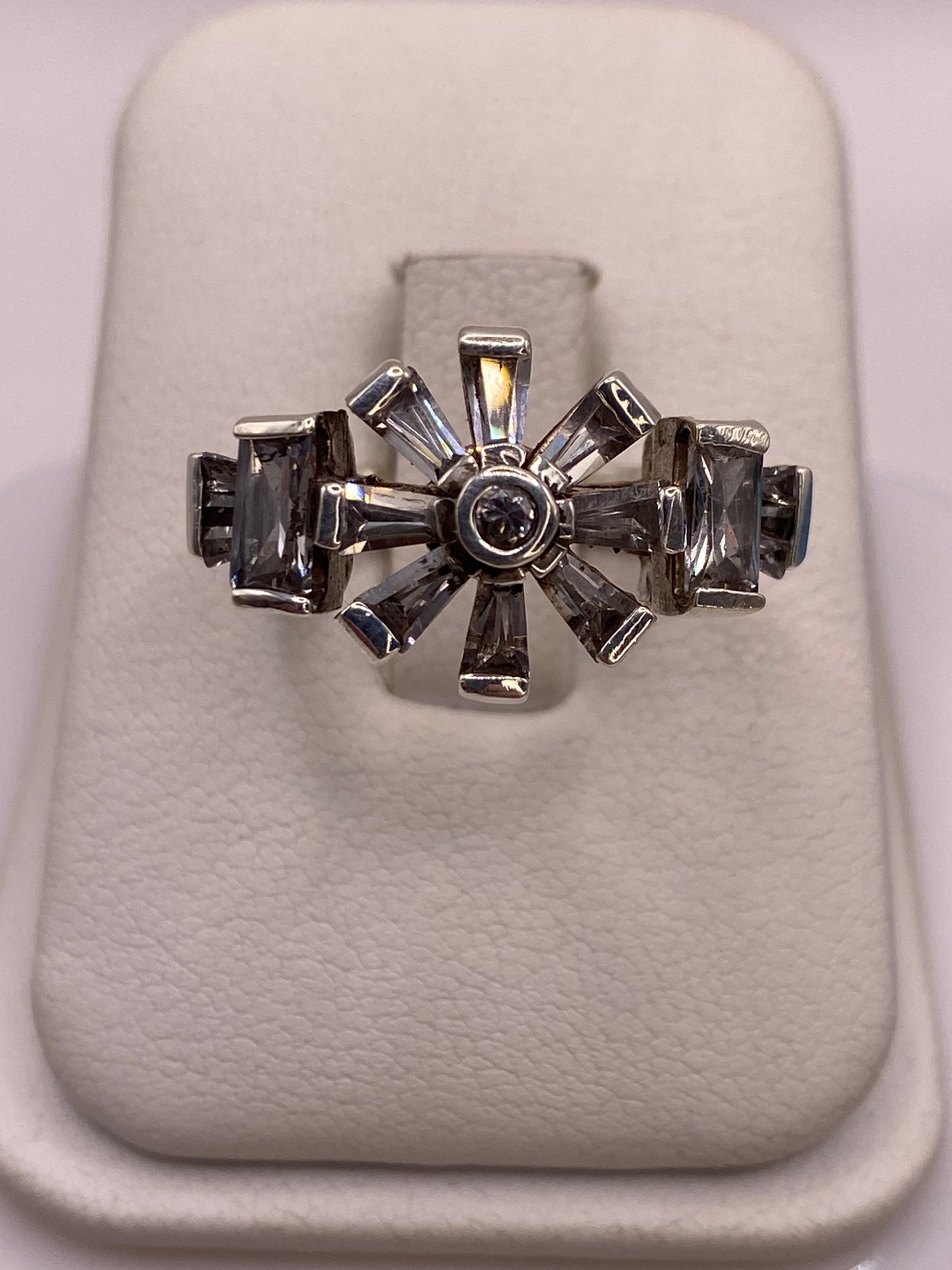 Anillo de plata .925 con arco de ocho circonias blancas y ahumadas, visto de frente sobre estuche blanco