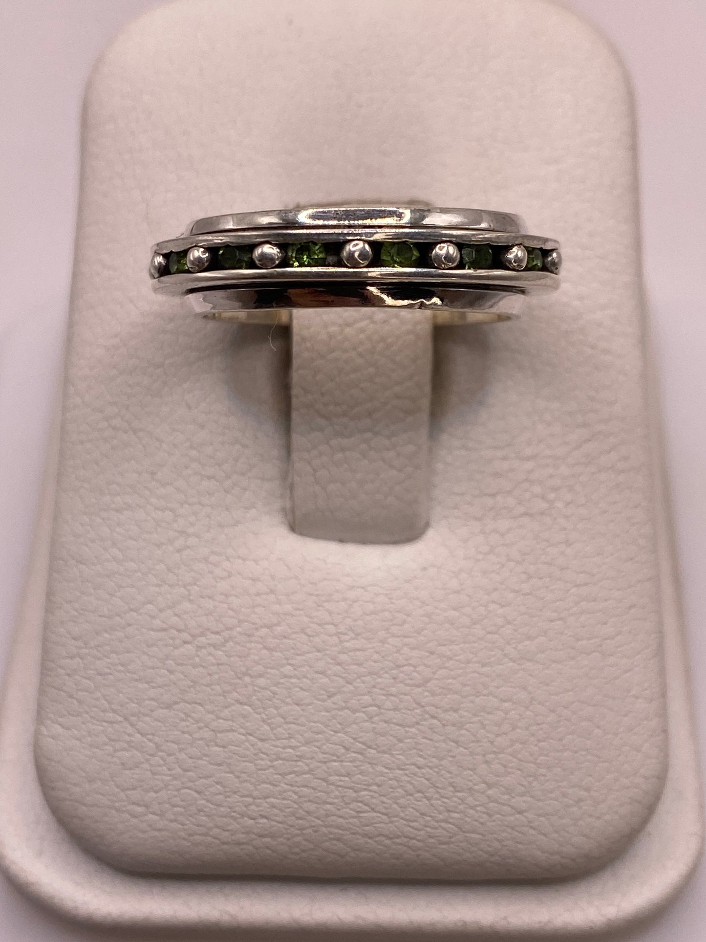 Anillo giratorio de plata .925 con circonias blancas y verdes en el dedo de una mujer
