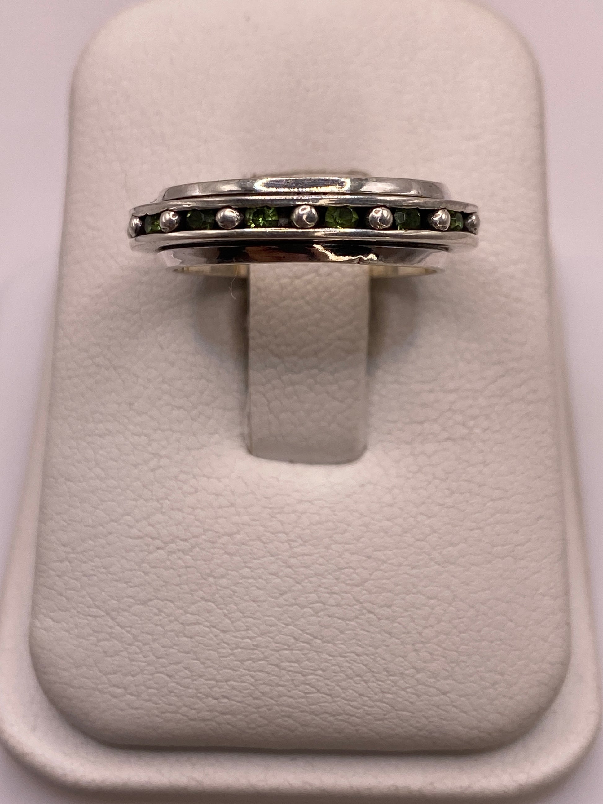 Anillo giratorio de plata .925 con circonias blancas y verdes en el dedo de una mujer