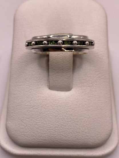 Anillo giratorio de plata .925 con circonias blancas y verdes en el dedo de una mujer