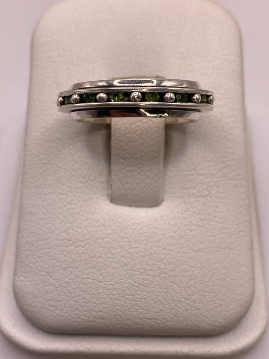Anillo giratorio de plata .925 con circonias blancas y verdes en el dedo de una mujer