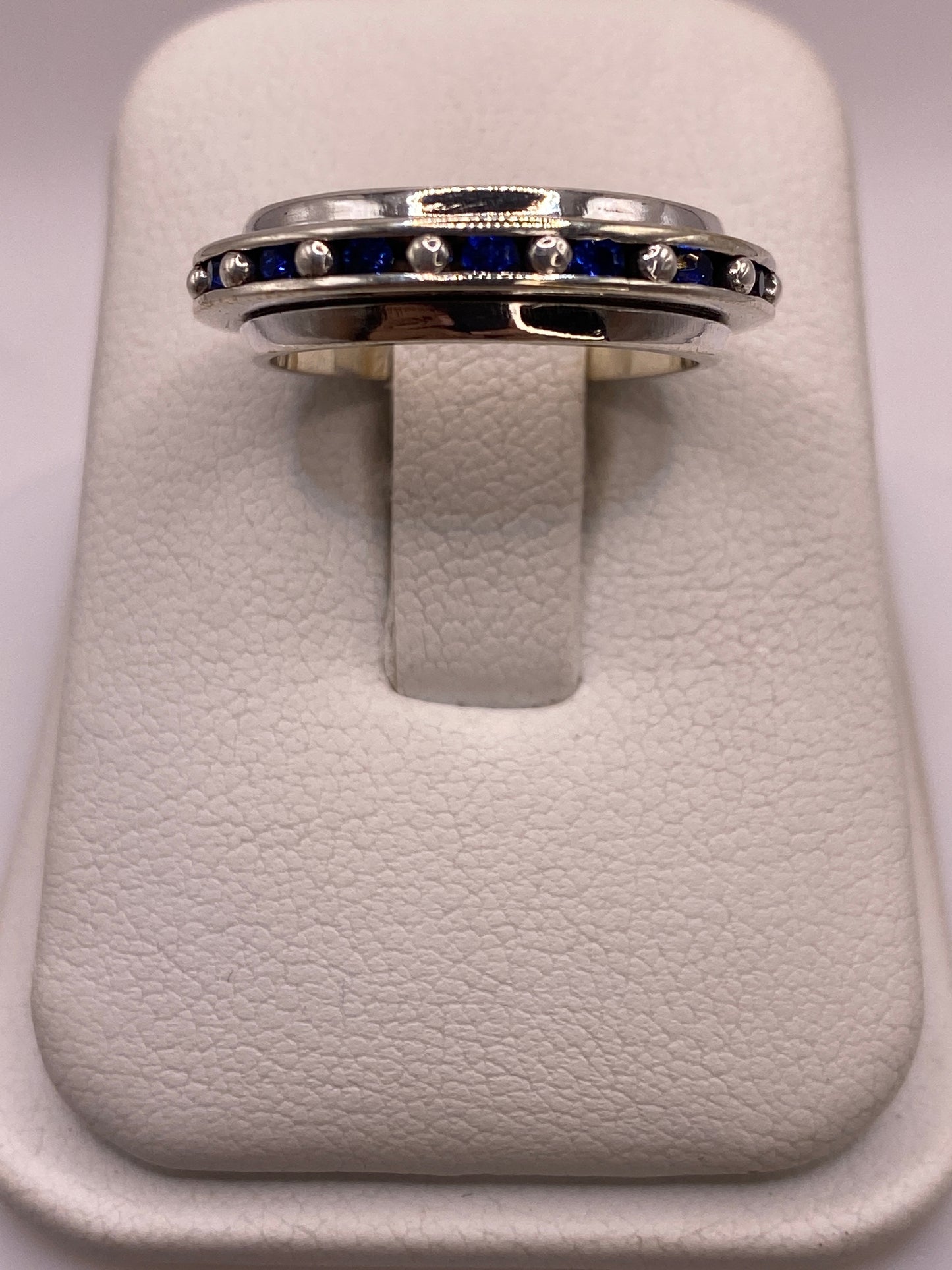 Anillo de plata con franja de circonias azules sobre fondo blanco, vista superior