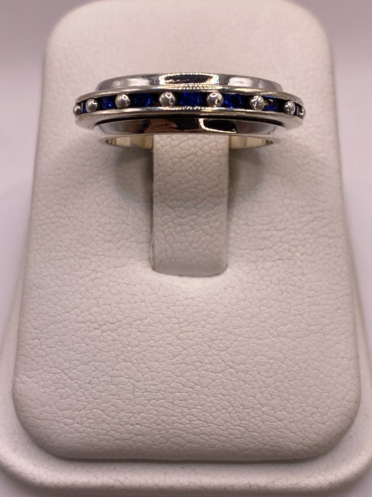 Anillo de plata con franja de circonias azules sobre fondo blanco, vista superior