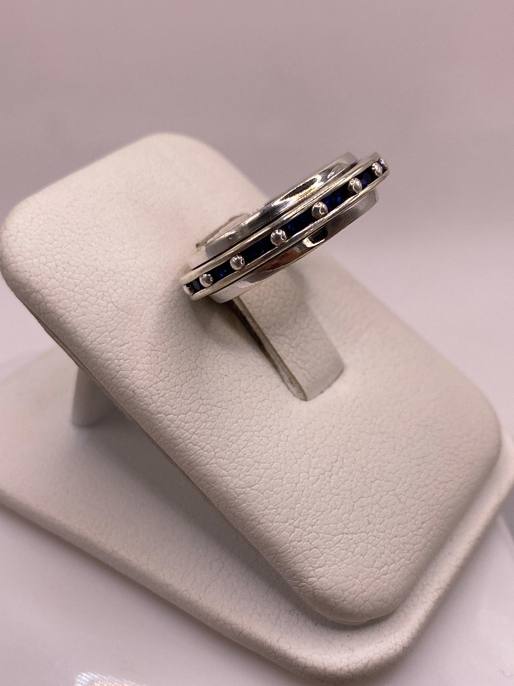 Anillo de plata clásico con circonias azules engastadas, vista lateral en mano