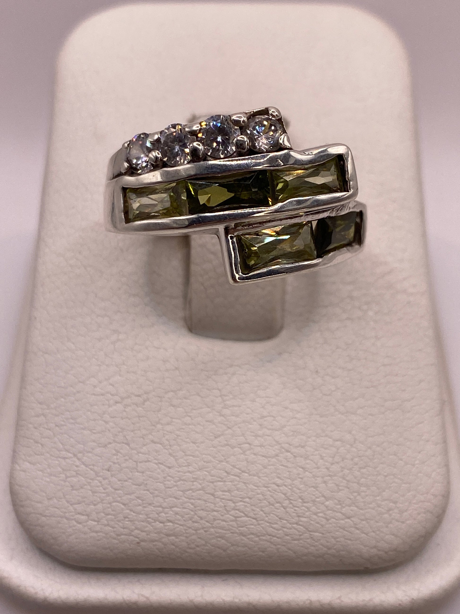Anillo de plata arquitectónico con dos filas de circonias blancas y verdes en la mano de una mujer