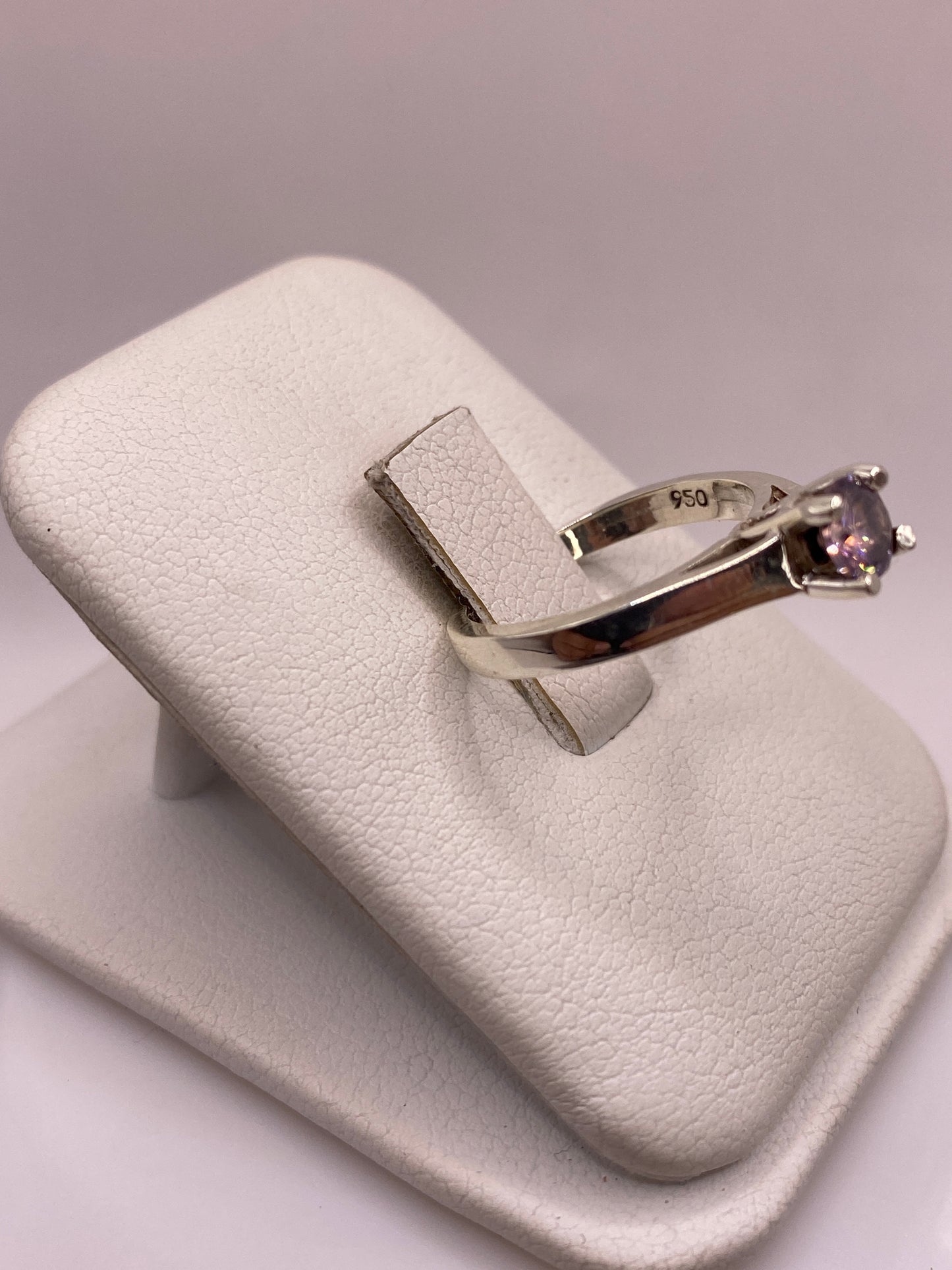 Anillo solitario visto de lado mostrando la banda lisa y el engaste de circonia morada