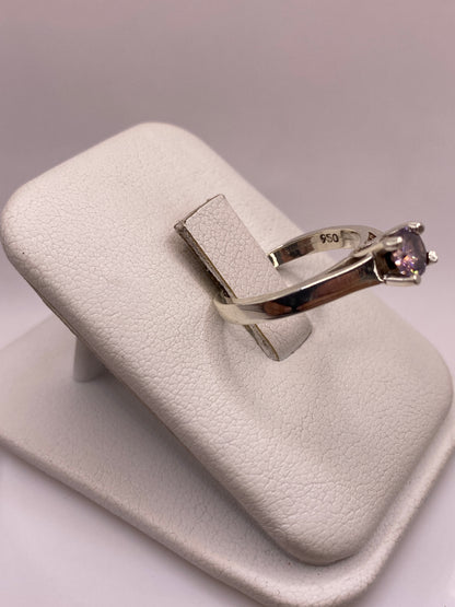 Anillo solitario visto de lado mostrando la banda lisa y el engaste de circonia morada
