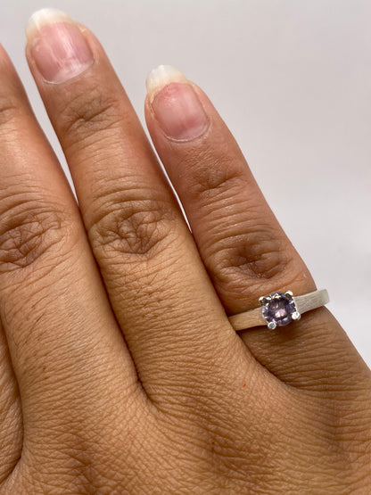 Anillo solitario puesto en dedo mostrando el tamaño y brillo de la piedra morada