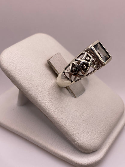 Anillo de plata con piedra cuadrada engastada en bezel, vista lateral mostrando banda texturizada