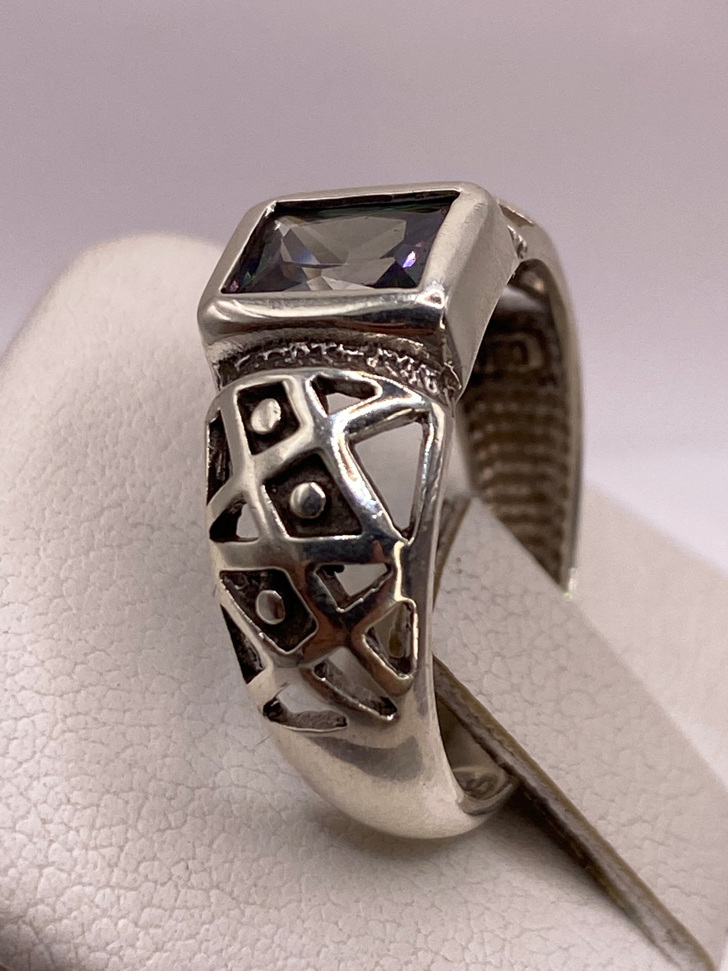 Detalle del anillo solitario en la mano, reflejando luz con fuego tipo diamante