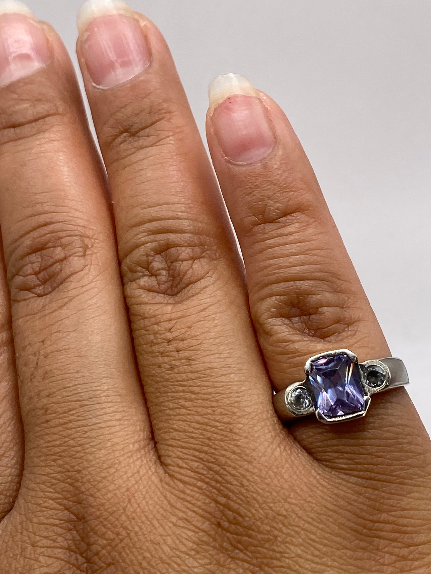 Anillo solitario violeta en la mano, mostrando brillo y profundidad de la piedra