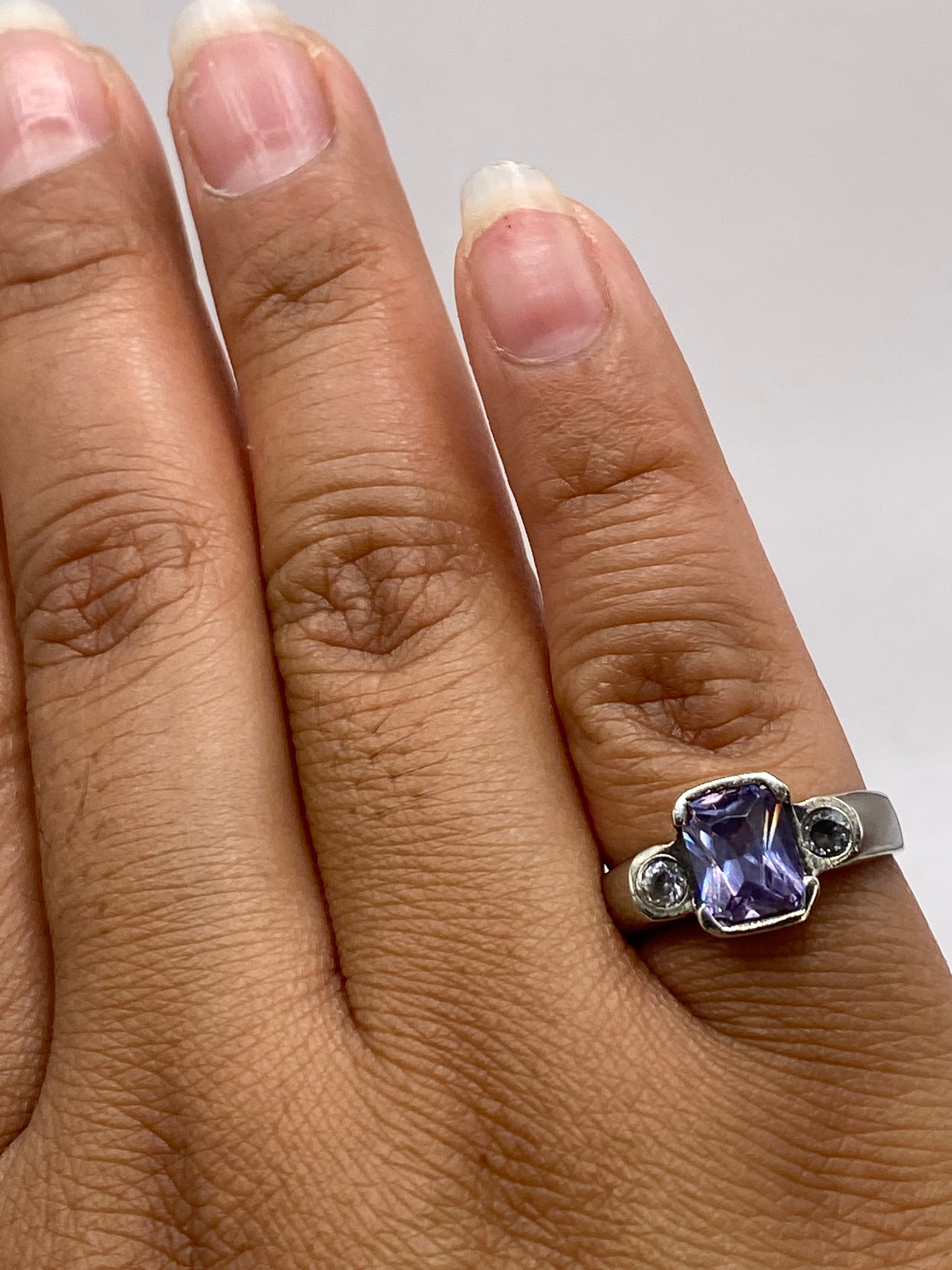 Anillo solitario violeta en la mano, mostrando brillo y profundidad de la piedra