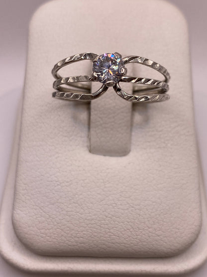 Anillo de plata solitario con circonia blanca brillante, diseño torneado en bandas entrelazadas