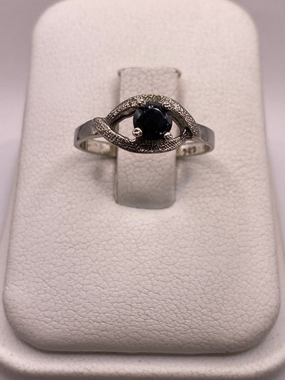 Anillo solitario de plata con circonia negra brillante, frente frontal sobre fondo blanco