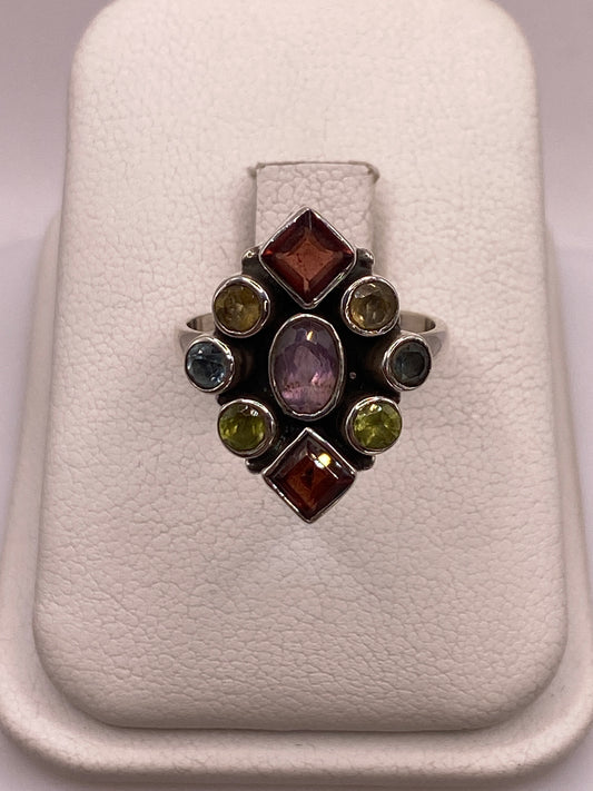 Anillo de plata vintage con circonias multicolor ámbar, verde, lila y gris en la mano de una mujer