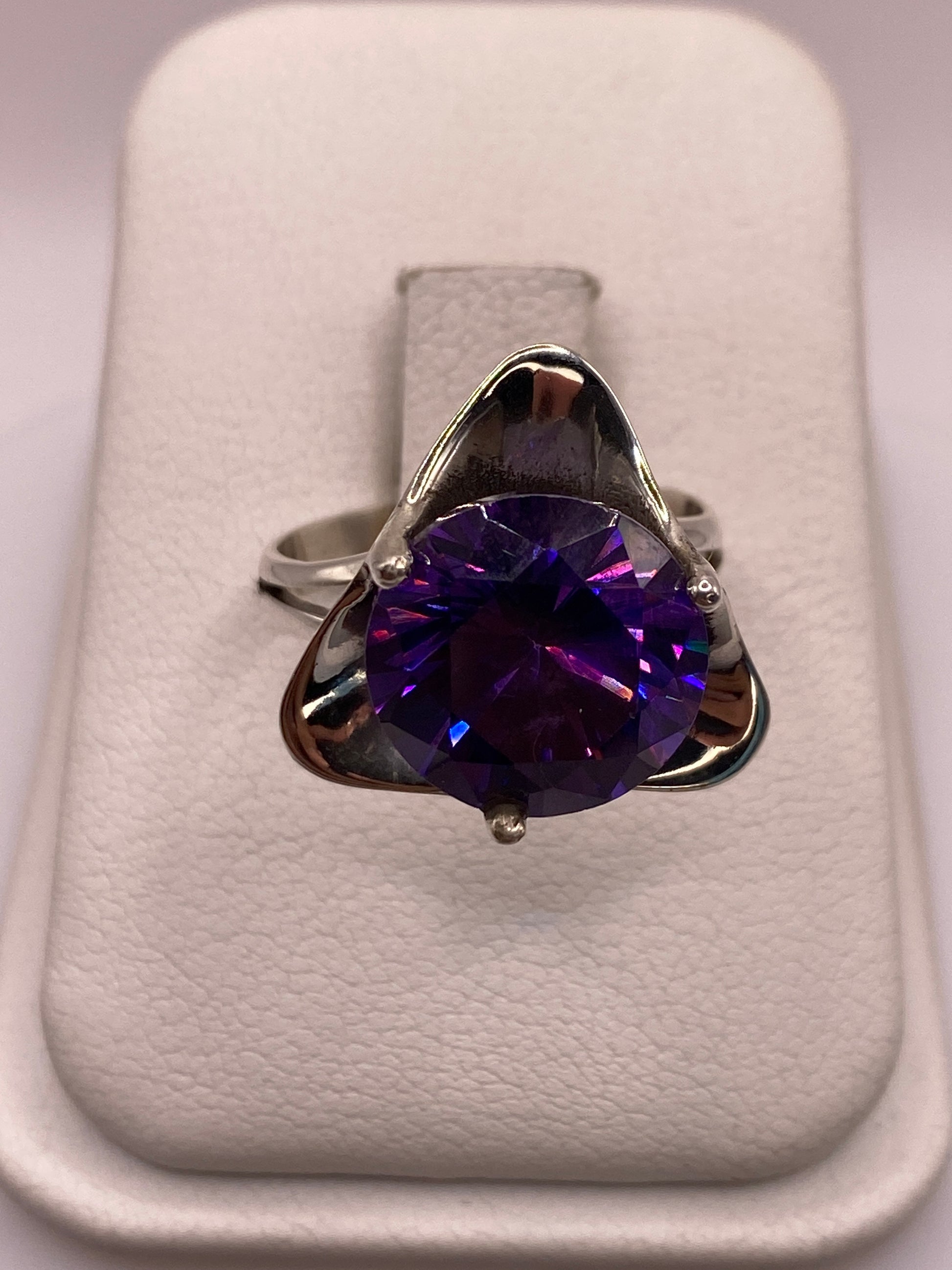 Anillo de plata solitario con circonia púrpura en engaste triangular, vista frontal en estuche blanco