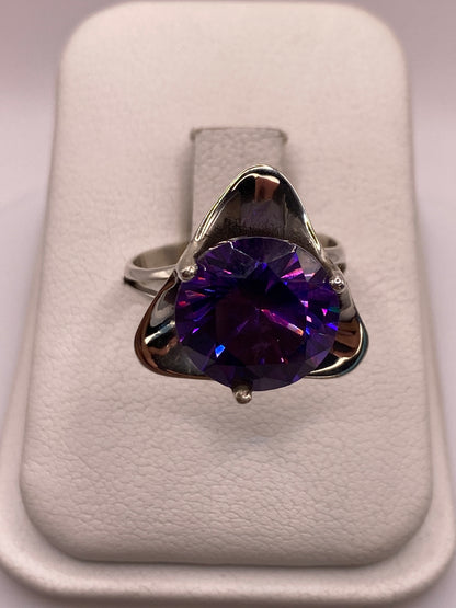Anillo de plata solitario con circonia púrpura en engaste triangular, vista frontal en estuche blanco