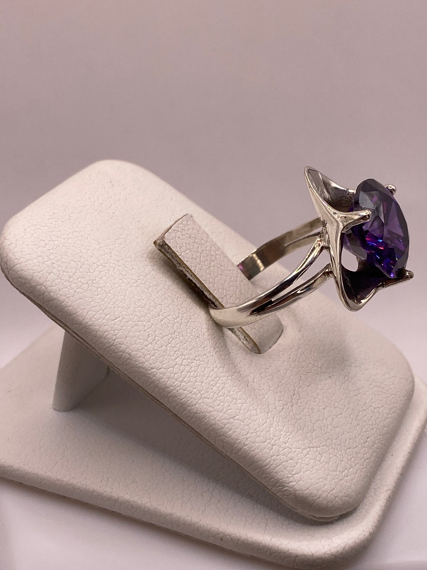 Anillo de plata con circonia púrpura visto de lado, mostrando el perfil del engaste y la banda