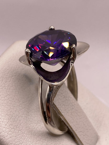 Anillo solitario de circonia púrpura en dedo de mujer, brillo multicolor bajo luz natural