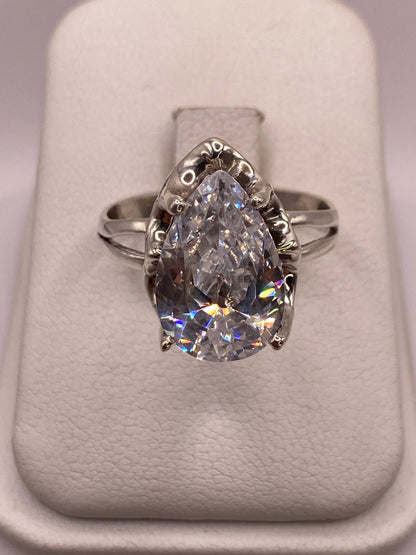 Anillo de plata solitario con circonia blanca corte gota, visto de frente sobre almohada blanca