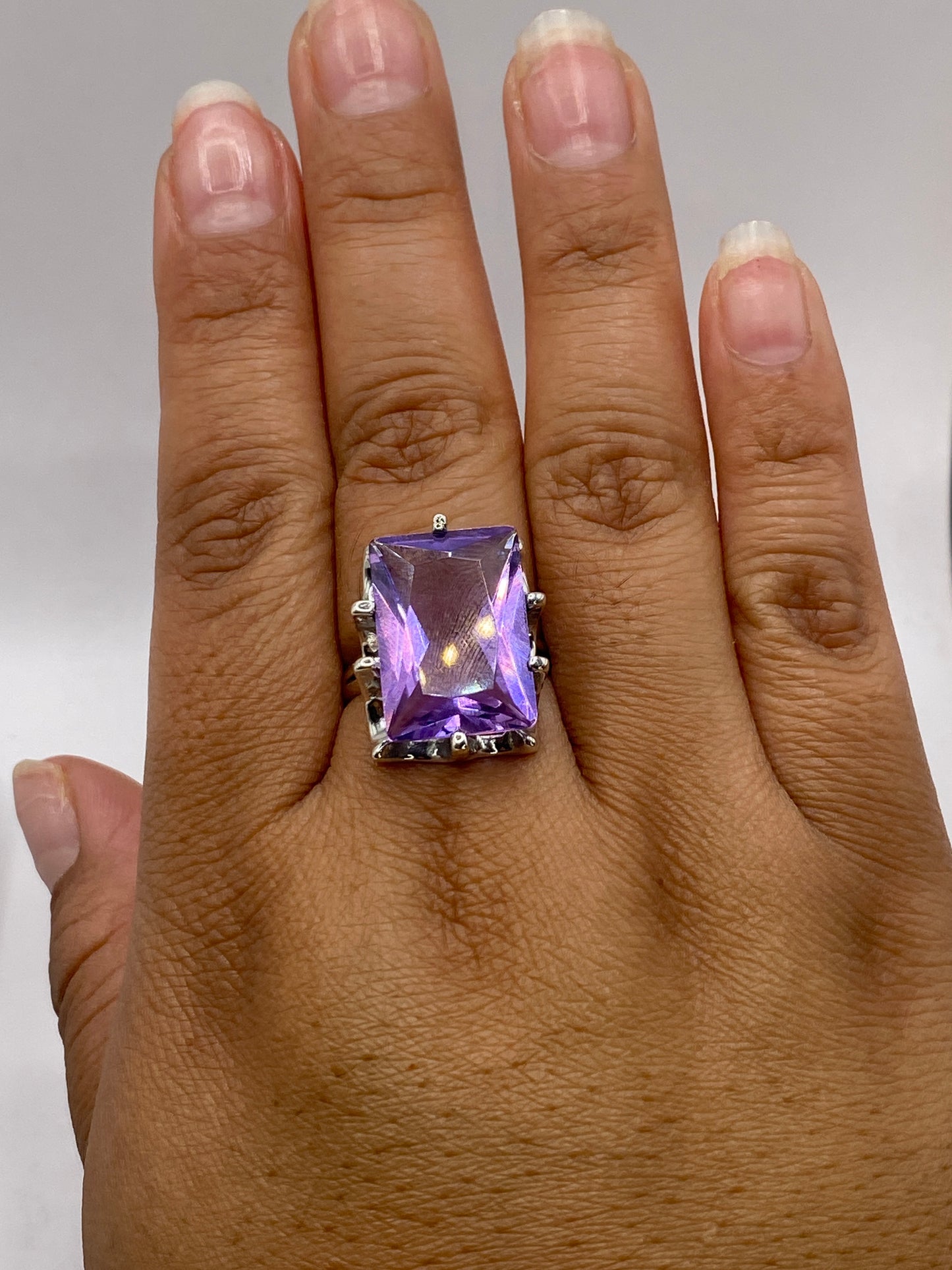 Anillo en dedo de mujer con sello 925 visible en la banda, luz reflejada en la piedra