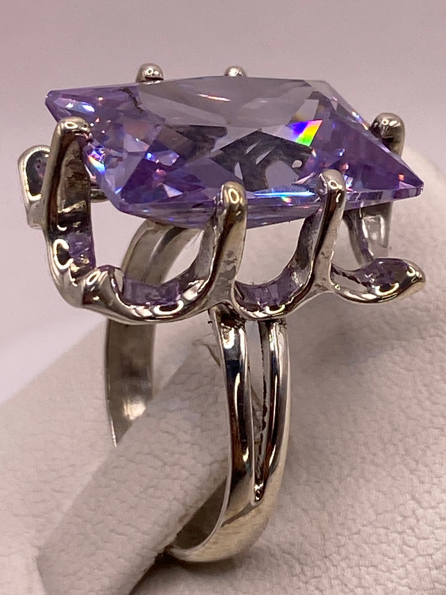 Anillo en la mano con la circonia púrpura reflejando luz azul y fuego tipo diamante