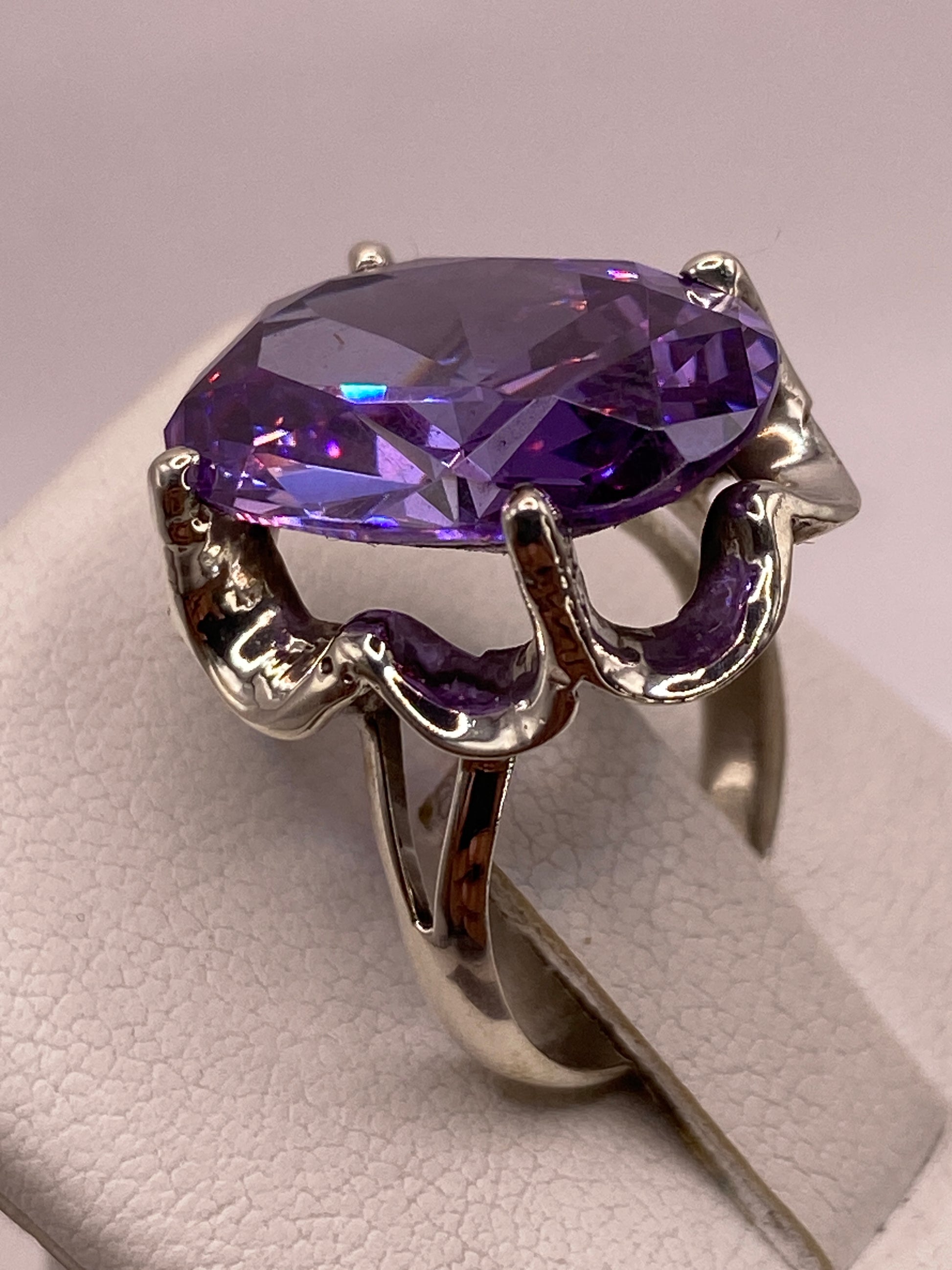 Anillo de plata con circonia púrpura en dedo femenino bajo luz natural