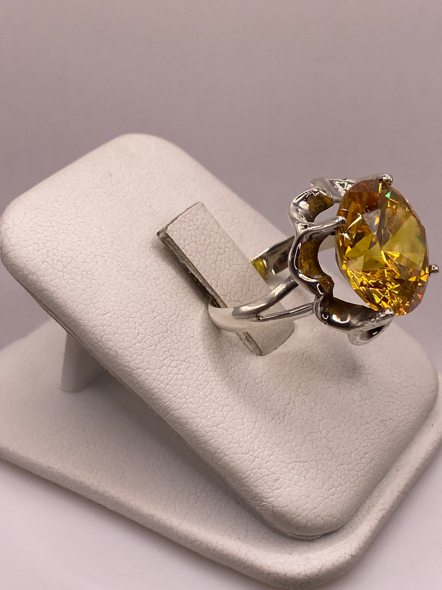 Anillo de plata .925 con circonia amarilla reflejando luz, portado en mano de mujer