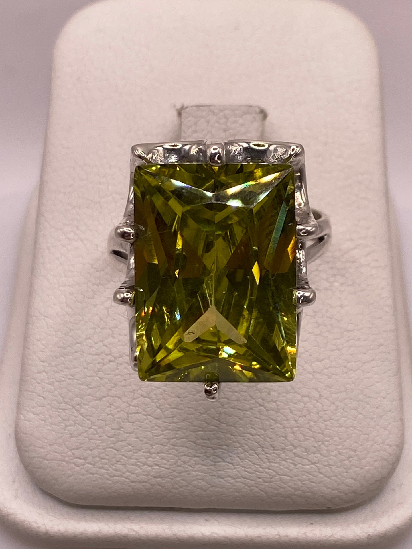 Anillo de plata con circonia amarilla rectangular en mano femenina, mostrando brillo tipo diamante