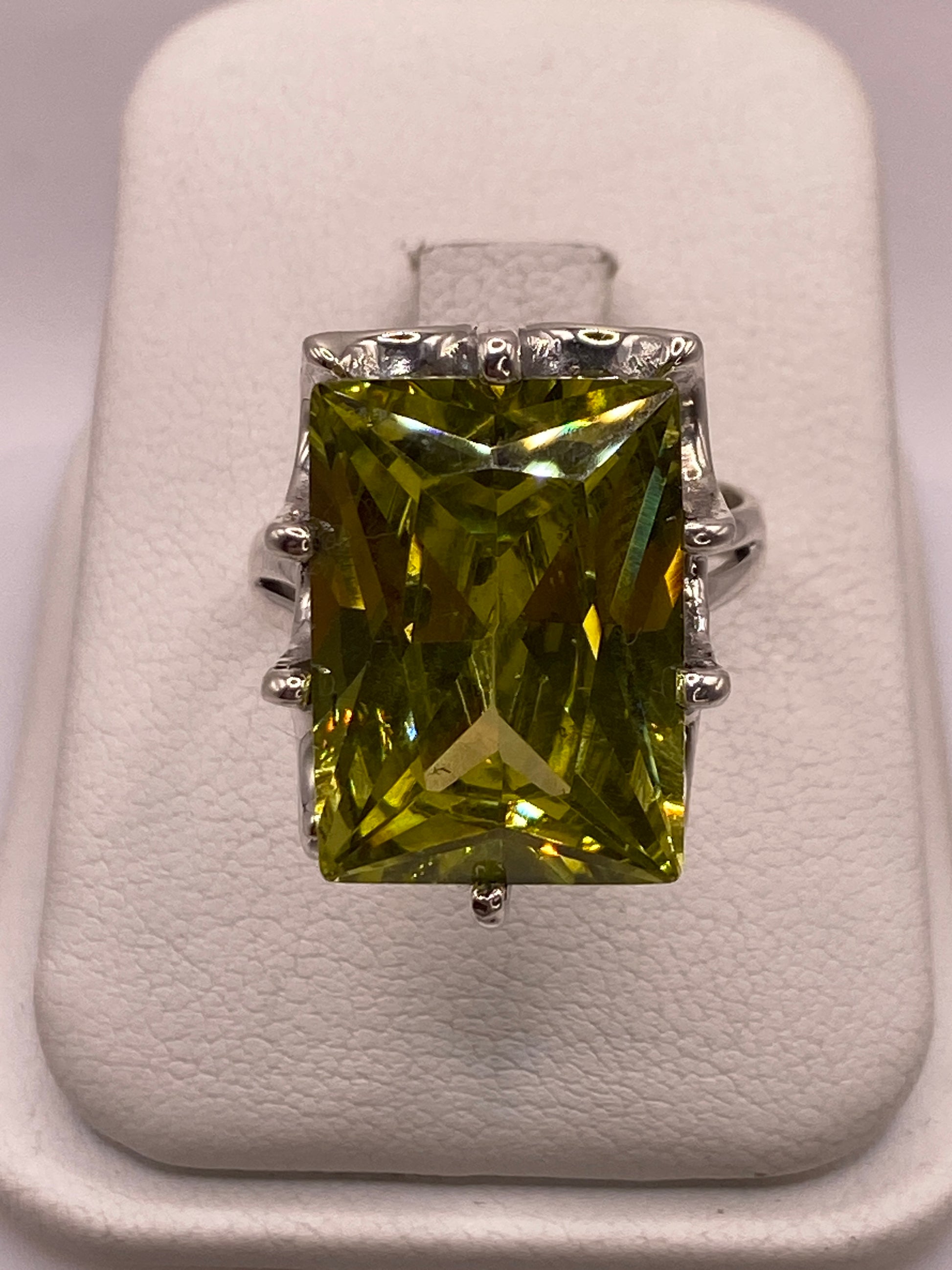 Anillo de plata con circonia amarilla rectangular en mano femenina, mostrando brillo tipo diamante