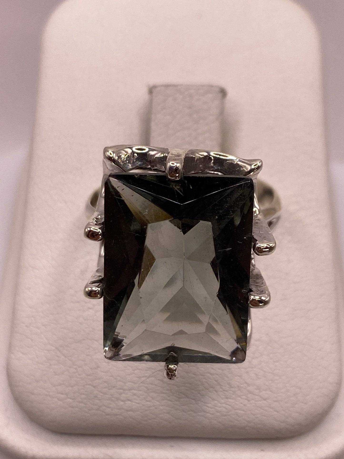 Anillo de plata solitario con circonia ahumada rectangular facetada en la mano de una mujer