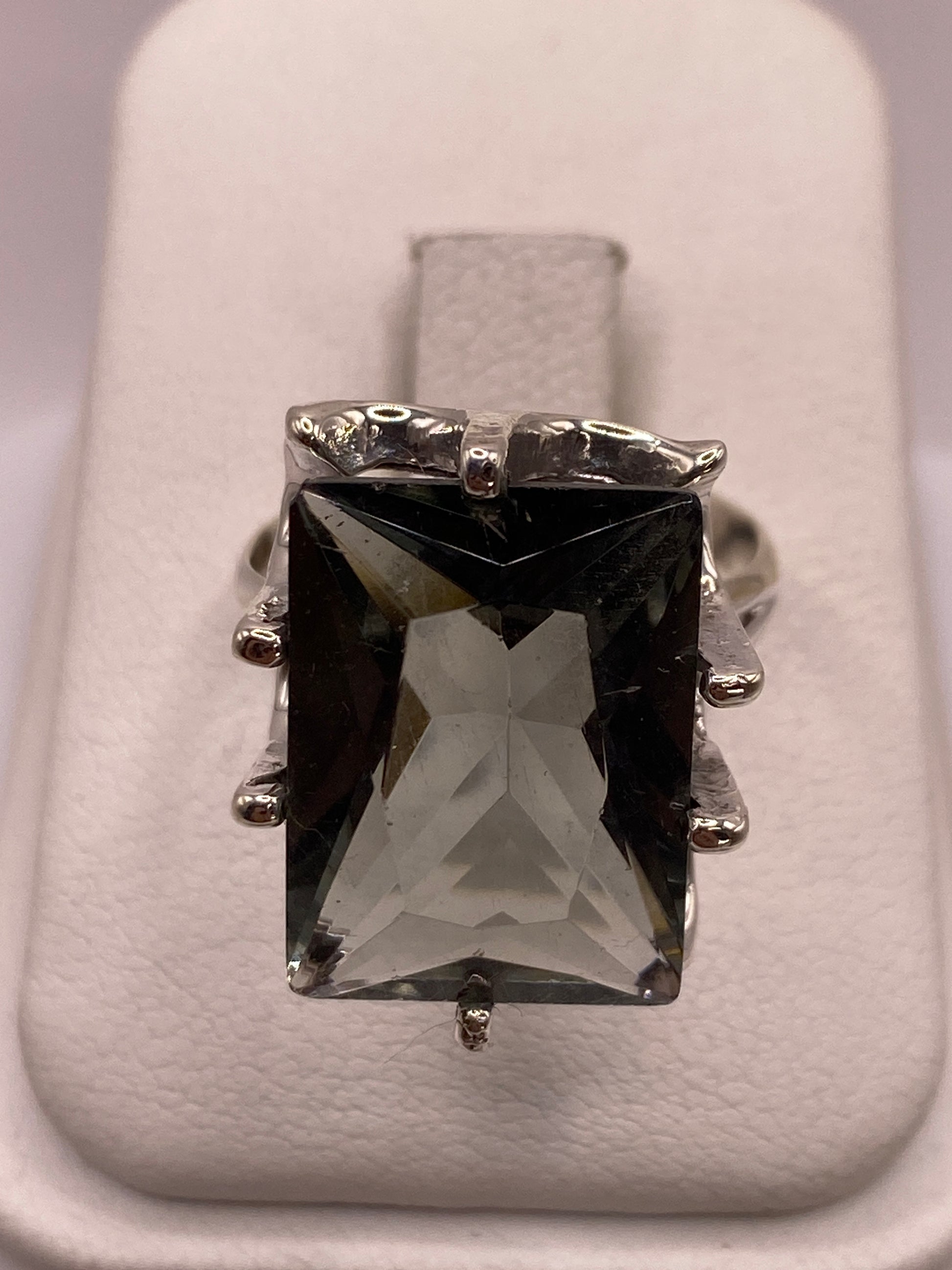 Anillo de plata solitario con circonia ahumada rectangular facetada en la mano de una mujer