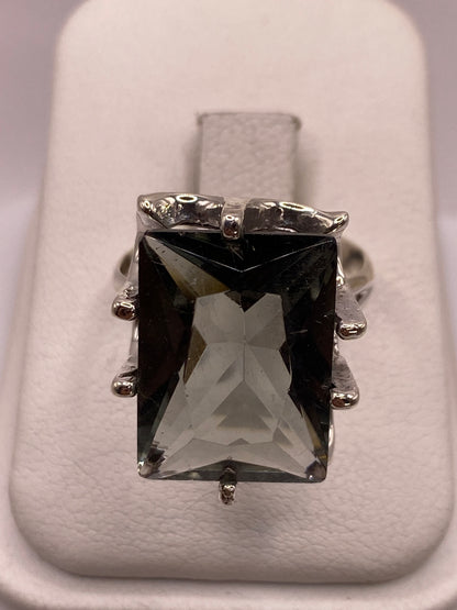 Anillo de plata solitario con circonia ahumada rectangular facetada en la mano de una mujer